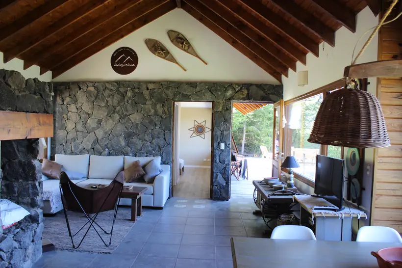 Living con pared de piedra y techo de madera